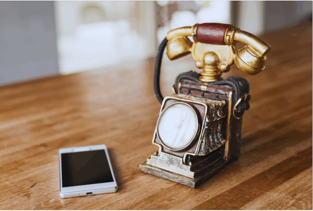 auf einem Tisch steht ein altes Telefon und daneben liegt ein Smartphone- Das Bild verdeutlich Transformation im Wandel der Zeit